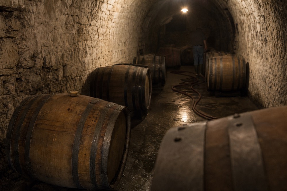 Barrel cellar with oak barrels resting on a stone floor in a Saint-Emilion chateau, no text, no logos, no people