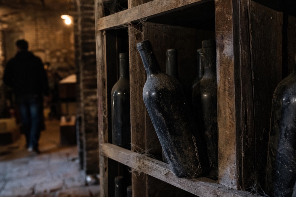 Close-up of wine bottles from classified Saint Emilion estates in a cellar rack, no text, no logos, no people